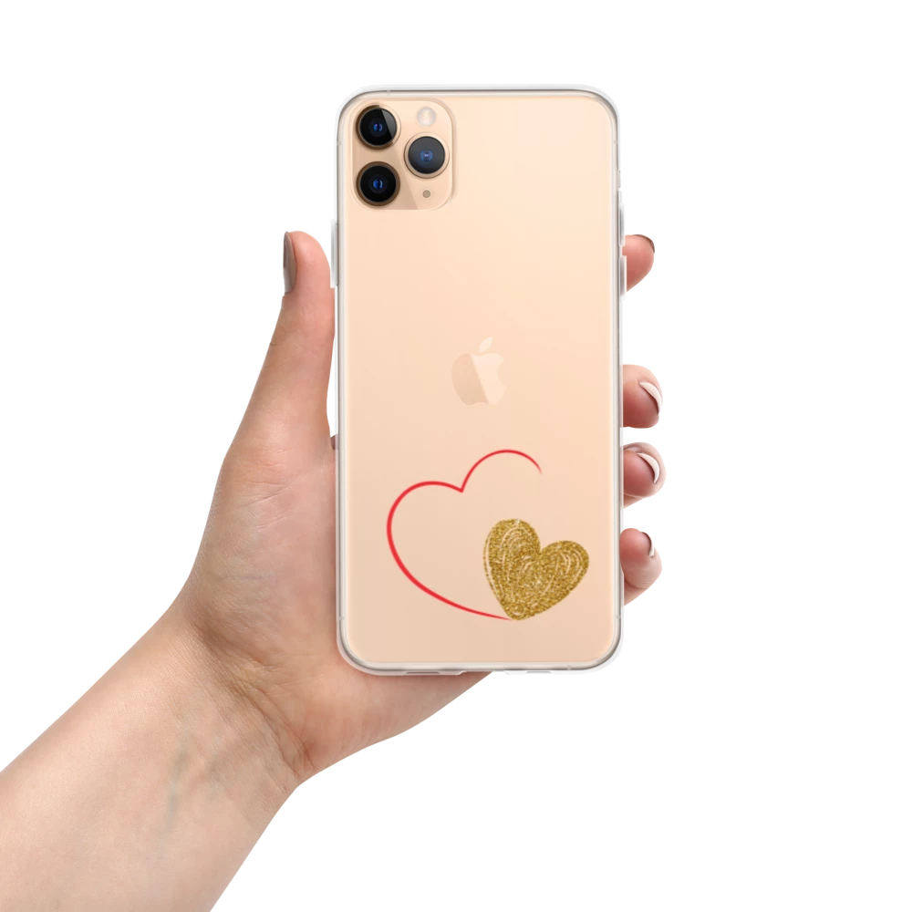 A hand holding a clear iPhone case with a gold heart and red accents design on the back.