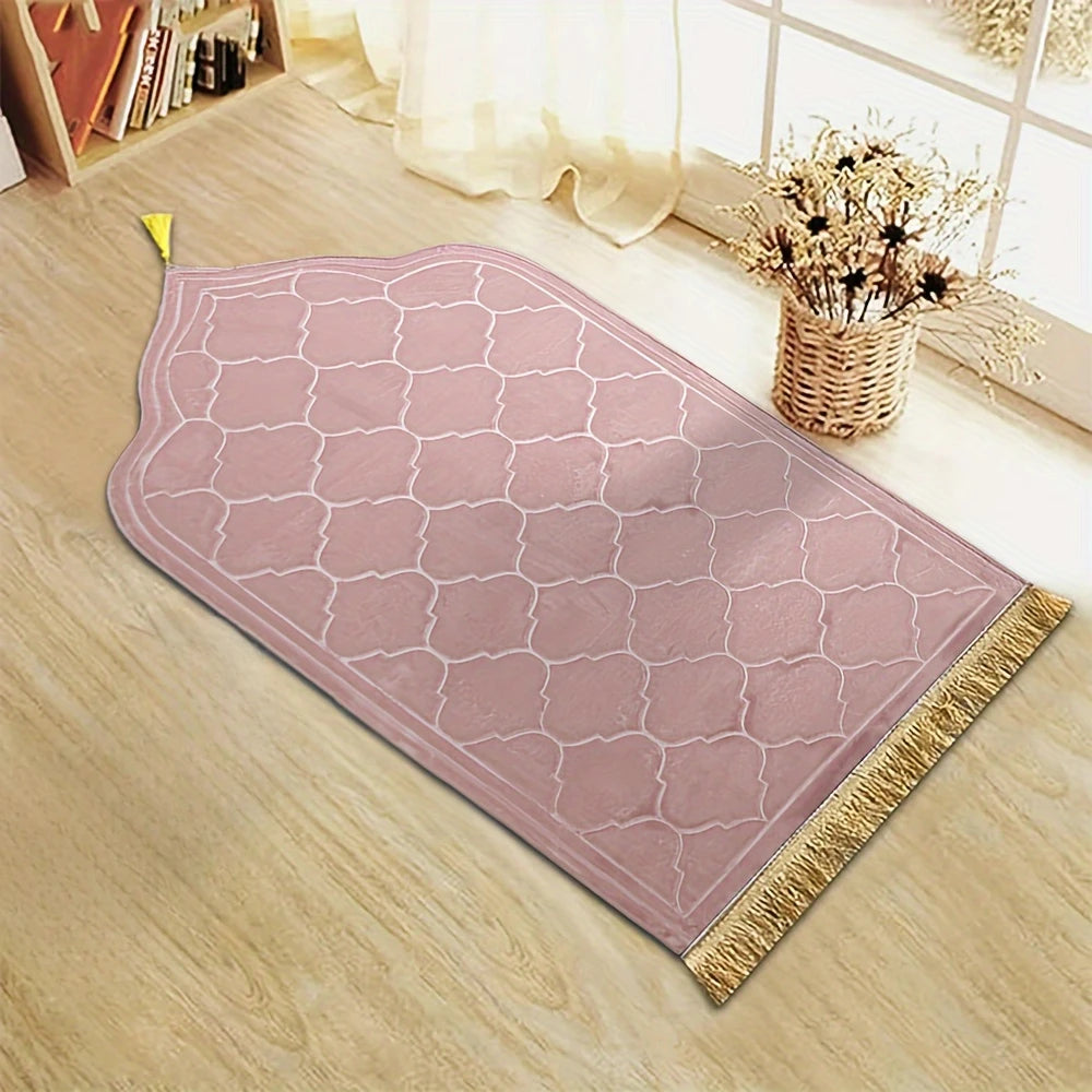 Pink prayer rug with tassels on a wooden floor.