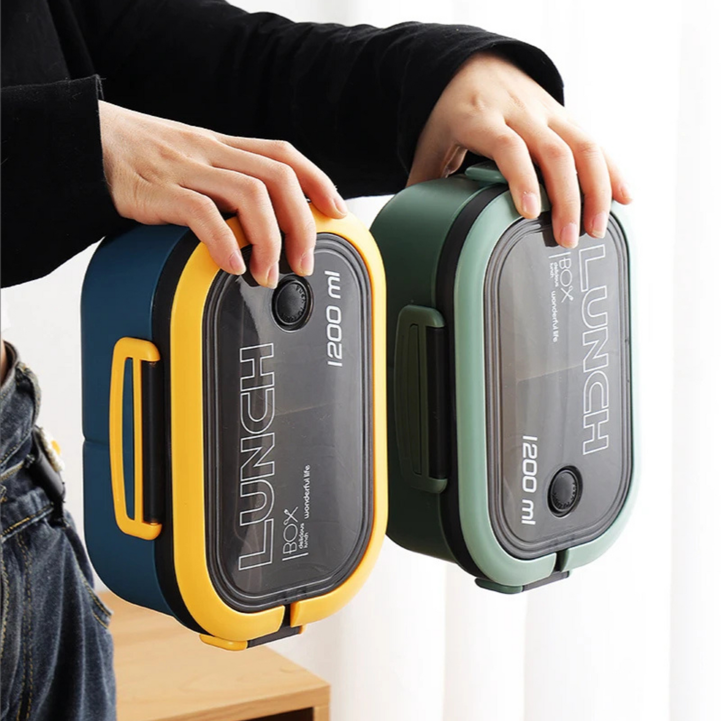 Blue and green lunch boxes held sideways to show leakproof design