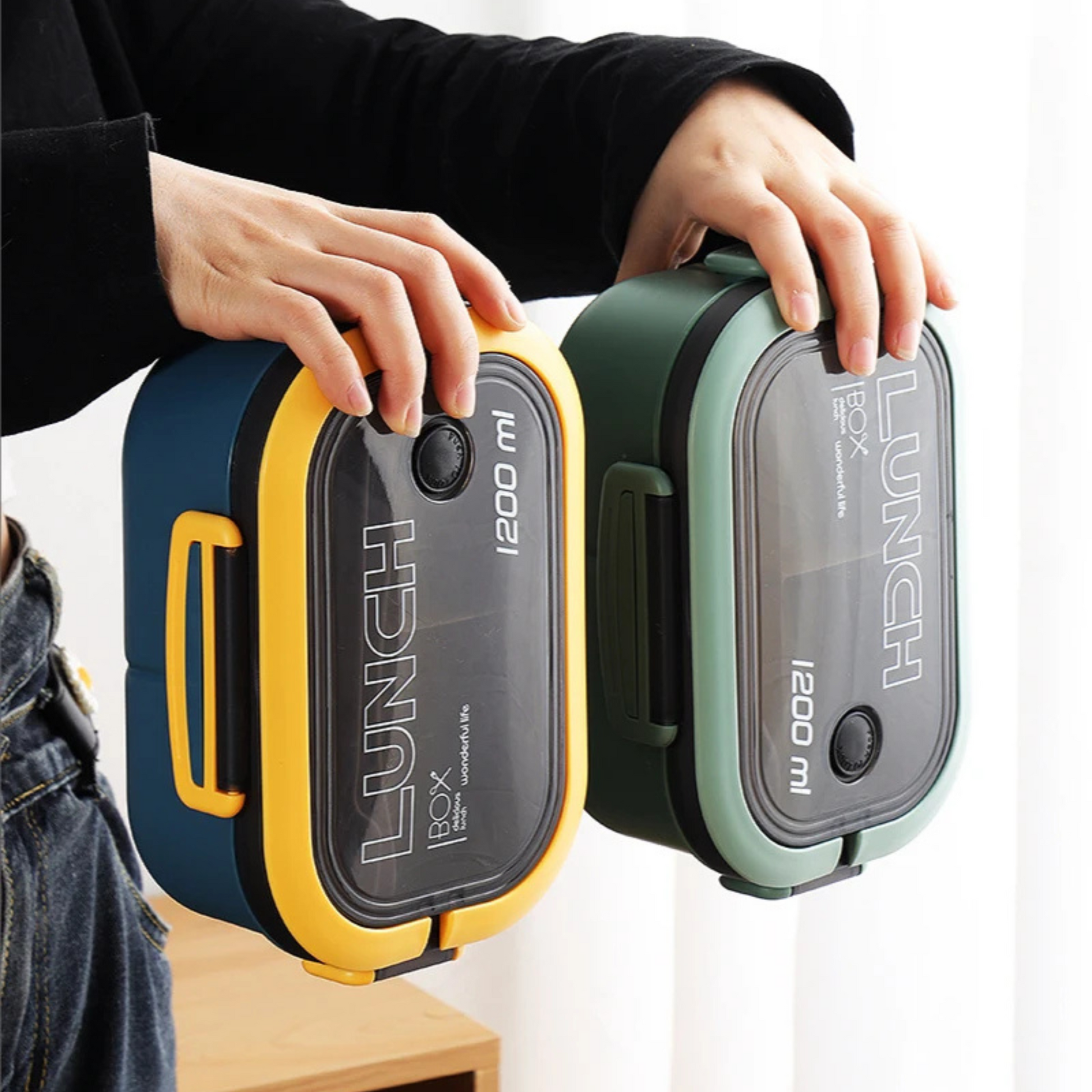 Blue and green lunch boxes held sideways to show leakproof design