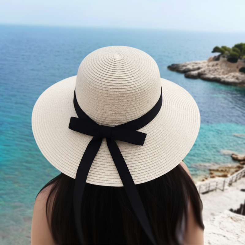 Woman wearing beige wide brim straw hat looking out over the sea – Mediterranean summer style