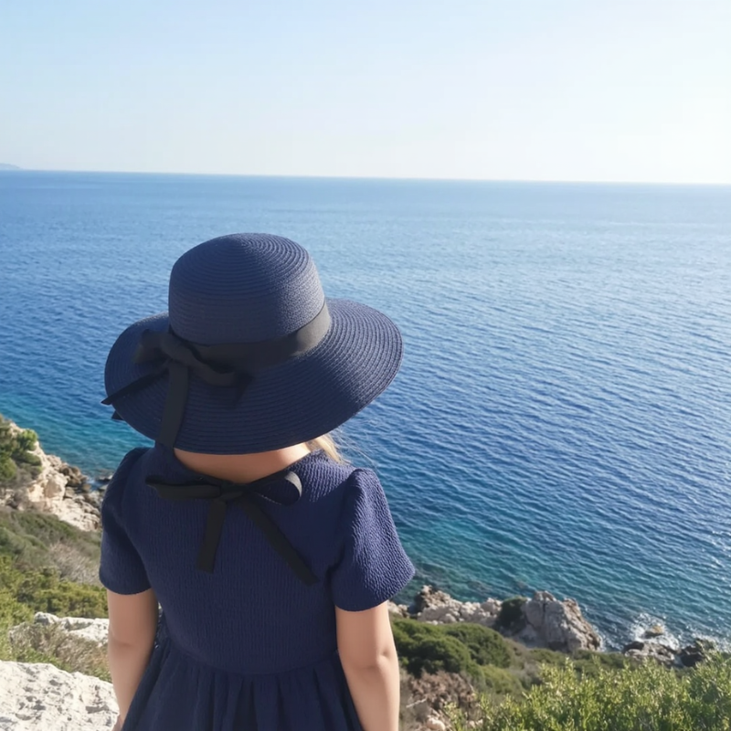 Blue wide brim straw hat worn by woman at seaside – UV-protective and foldable for travel ease