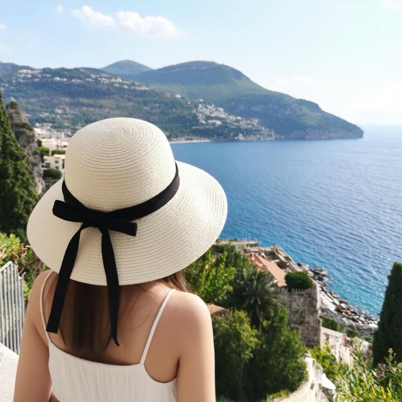 Woman wearing milk white sun hat by the sea – packable wide brim hat with relaxed holiday style