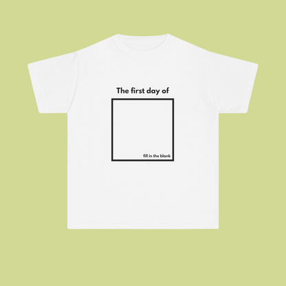 White t-shirt with text 'The first day of fill in the blank' on a light green background