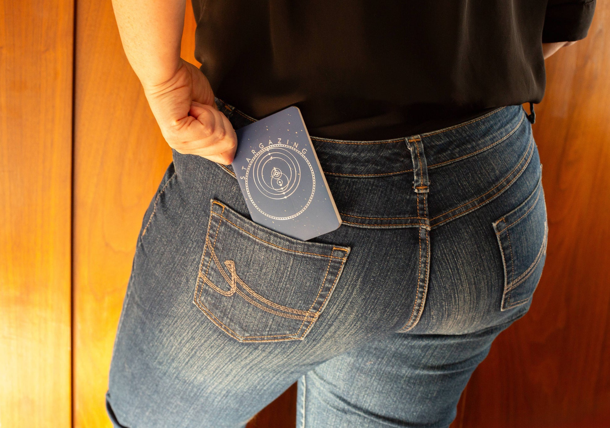 Pocket size Stargazing Notebook being placed into back pocket of jeans